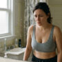 how to prevent boobs from sagging — woman concerned about sagging breasts looking in bathroom mirror