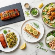salmon recipes for lean body — flat lay of multiple healthy salmon meal recipes on marble surface